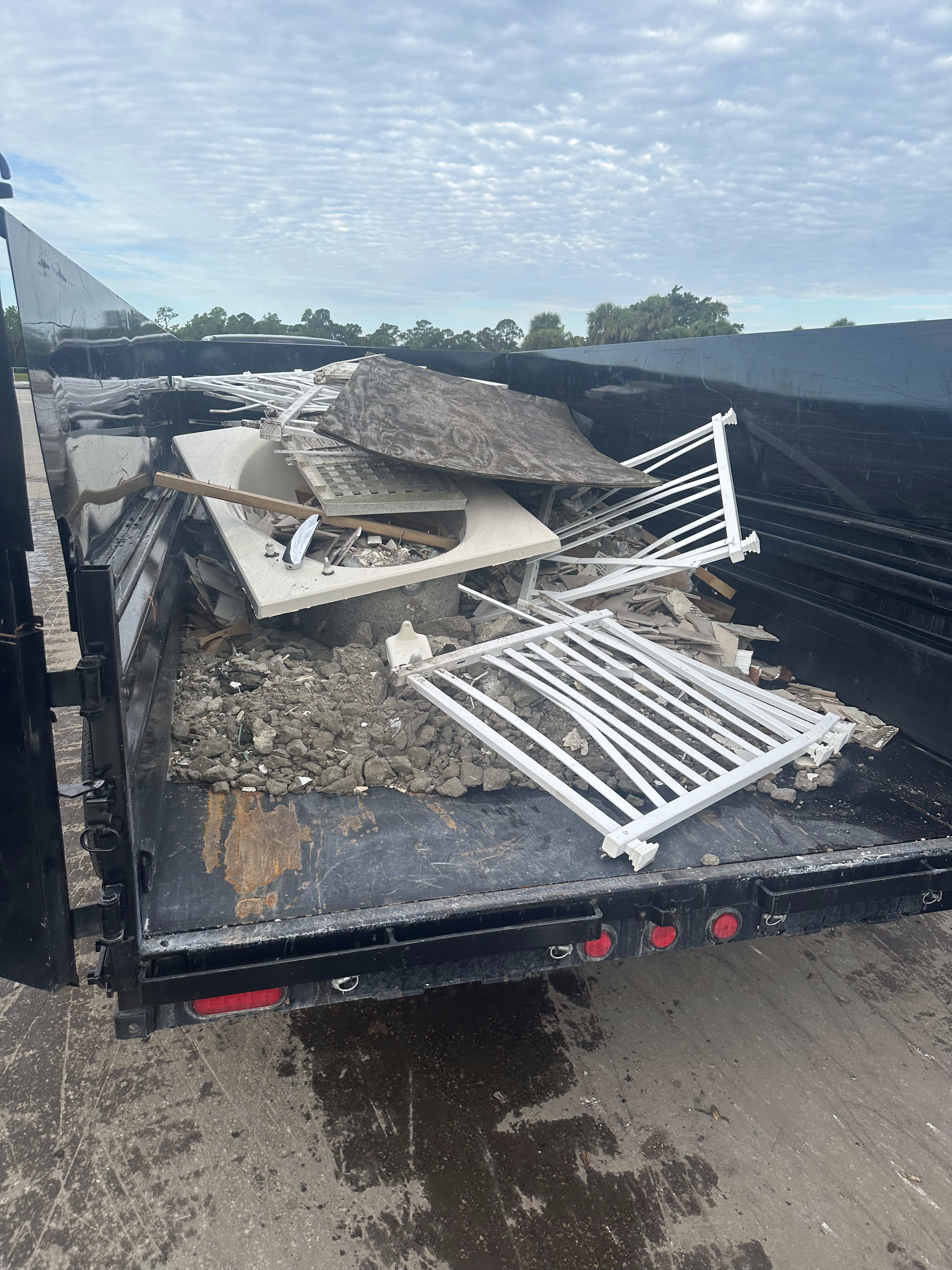A dumpster filled with a lot of trash and a fence.