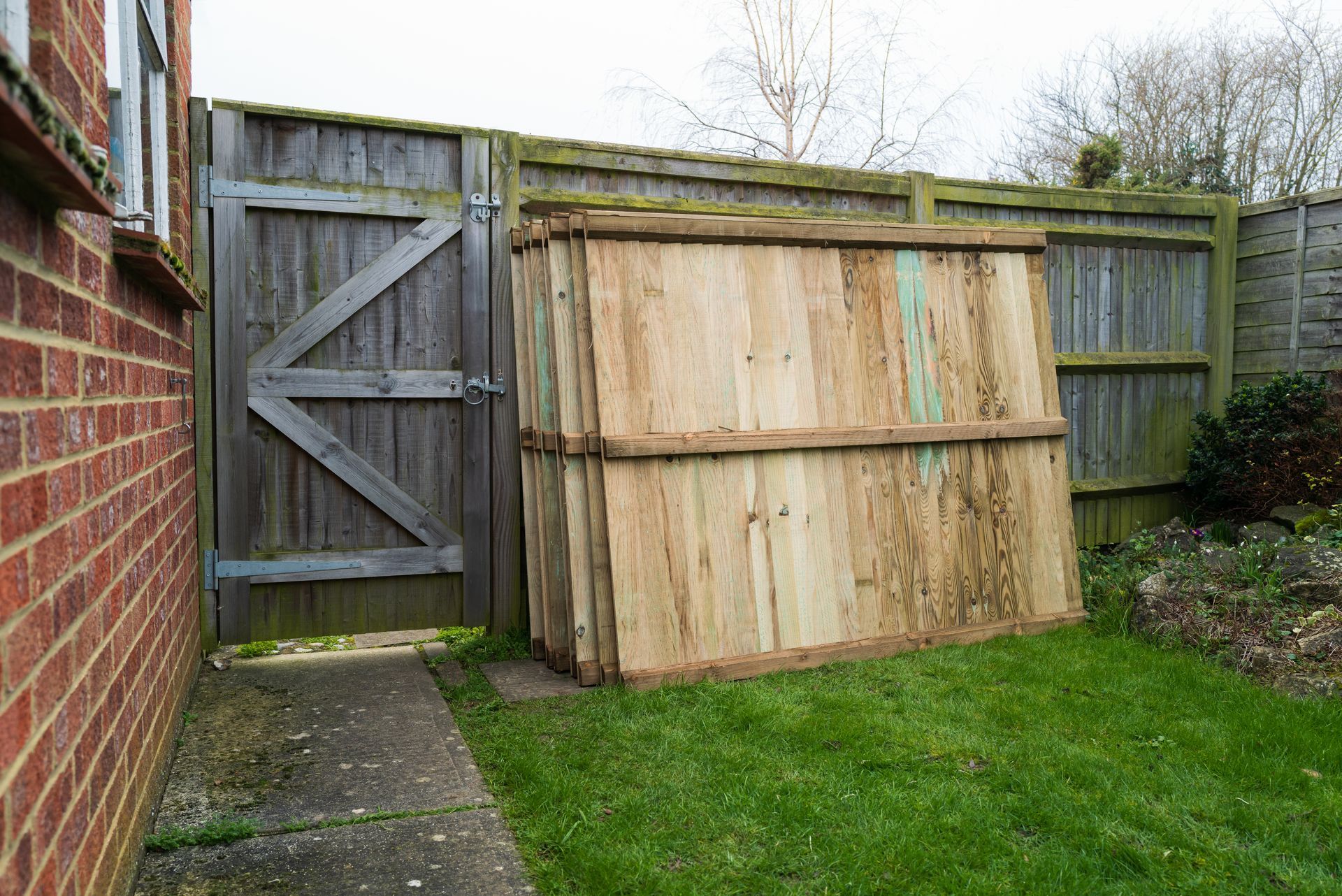 A wooden fence with a gate in the backyard of a house.