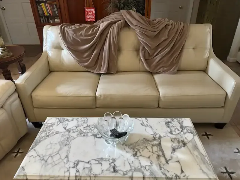Beige sofa with draped taupe fabric behind a marble coffee table in a living room