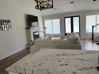 Modern living room with white sofas, large windows, TV, and a patterned rug