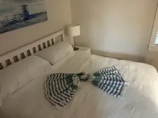 Neatly made white bed with striped bow, bedside lamp, and wall art in a bright bedroom