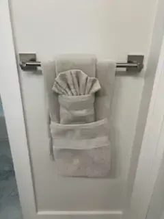 Gray hand towel folded on a chrome towel ring hanging on a white bathroom door