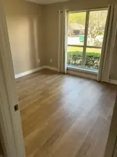 Empty room with wood floors and a large window overlooking greenery