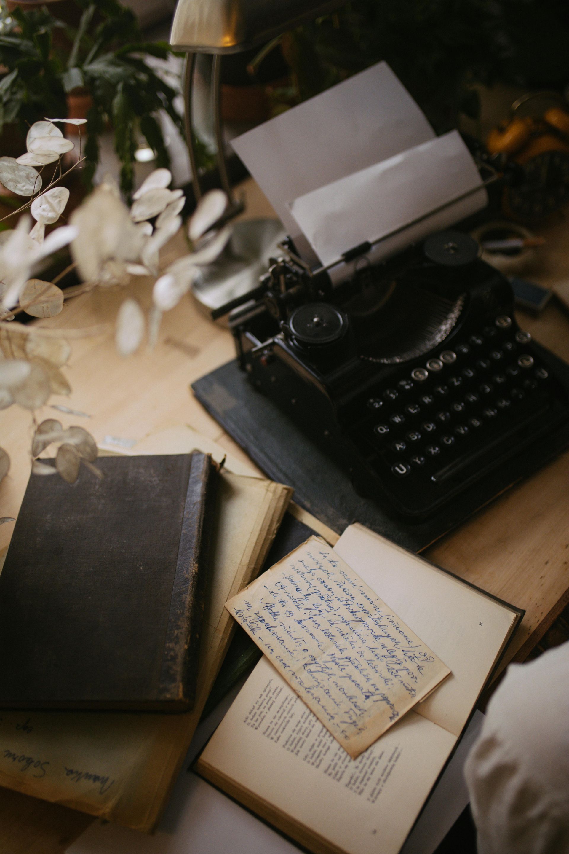 Vintage typewriter on a desk with books and handwritten letter.