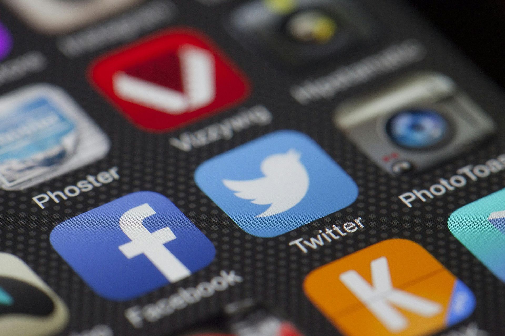 Close-up of a smartphone screen with social media app icons, including Facebook and Twitter.