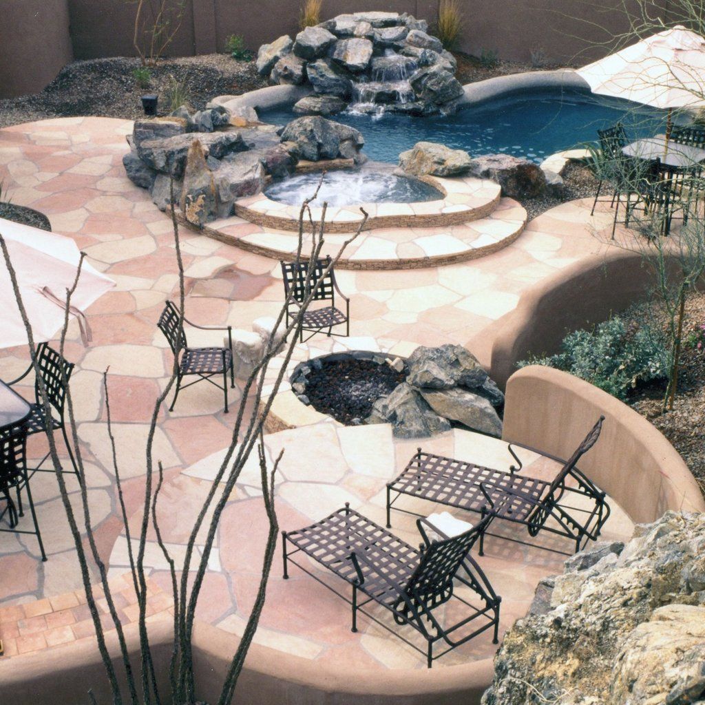 Patio with metal chairs, fire pit, and stone-lined swimming pool in a desert-style backyard