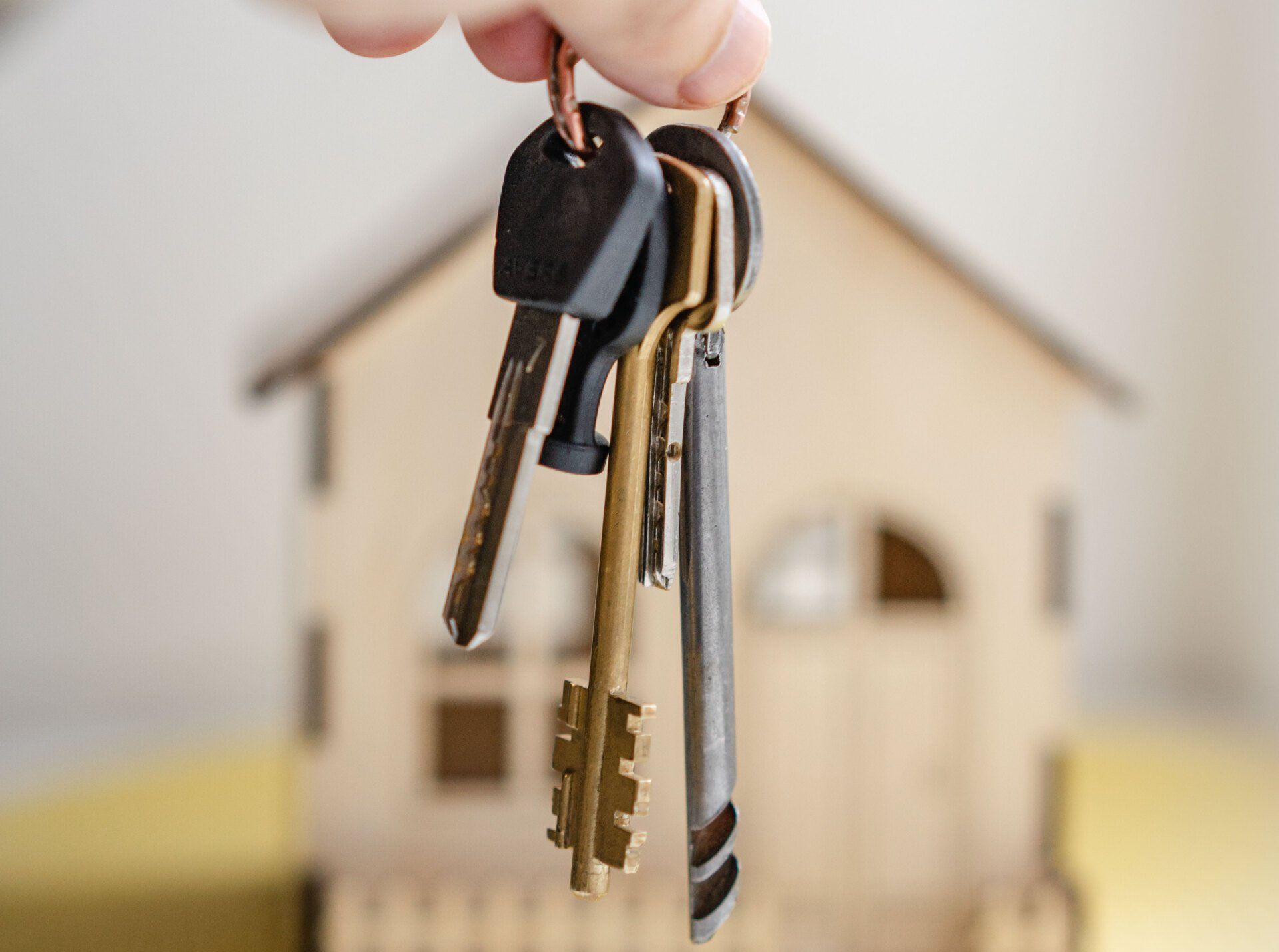 a person is holding a bunch of keys in front of a model house .