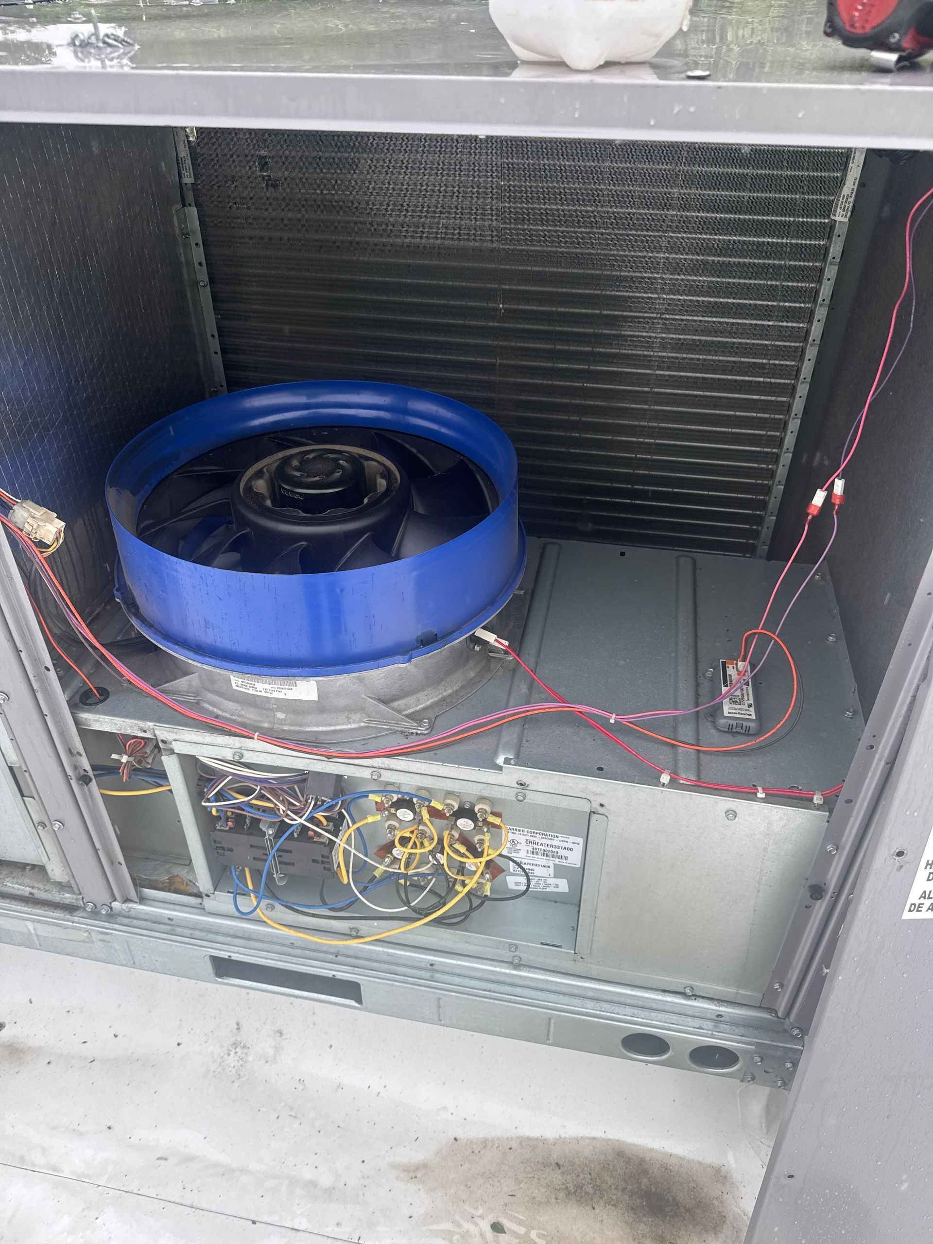 Blue and black fan inside an open metal cabinet with exposed wiring and insulation panels