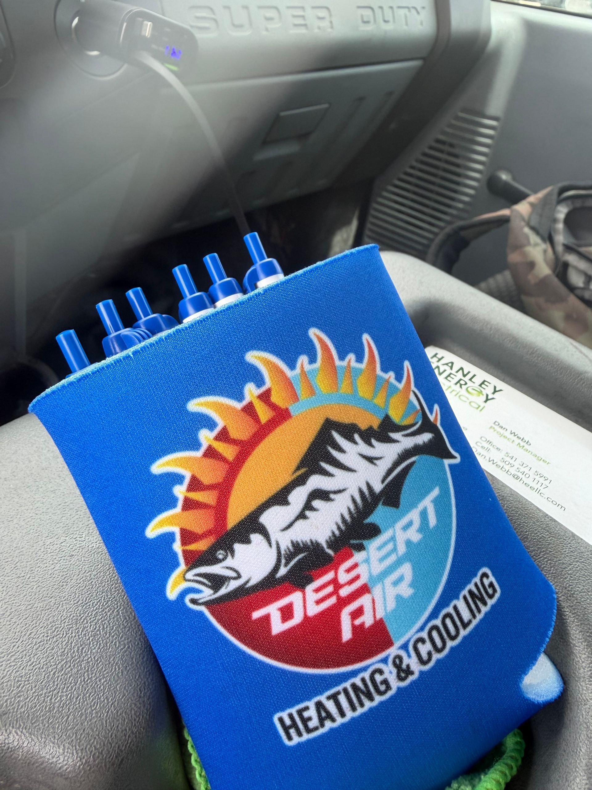 Blue Desert Air HVAC vent clip with sun-and-wave logo attached to a car dashboard vent.