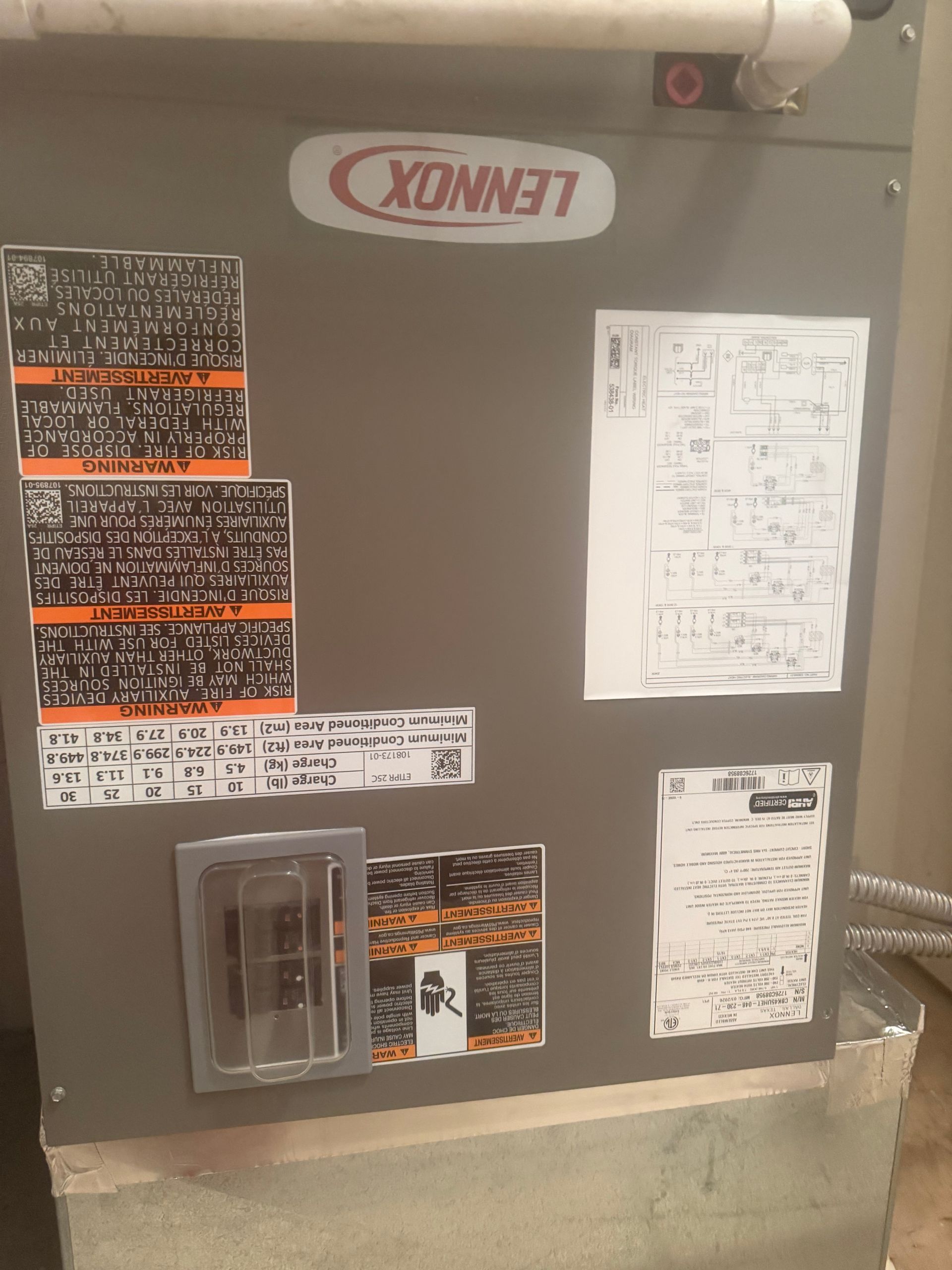 Gray Lennox HVAC unit with posted service labels and diagrams on the front panel.