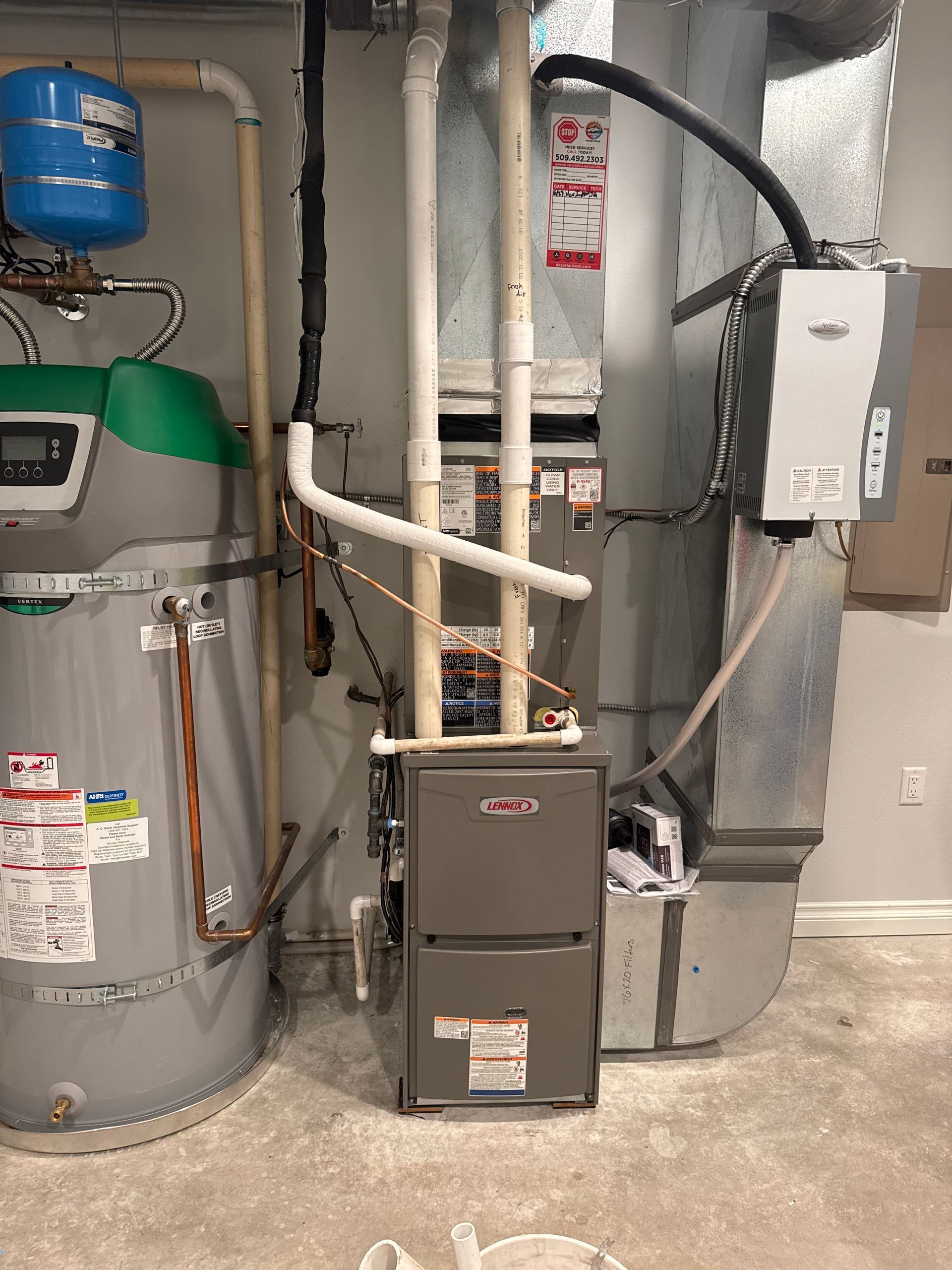Basement water heater and furnace units with pipes, ductwork, and utility boxes in a utility room