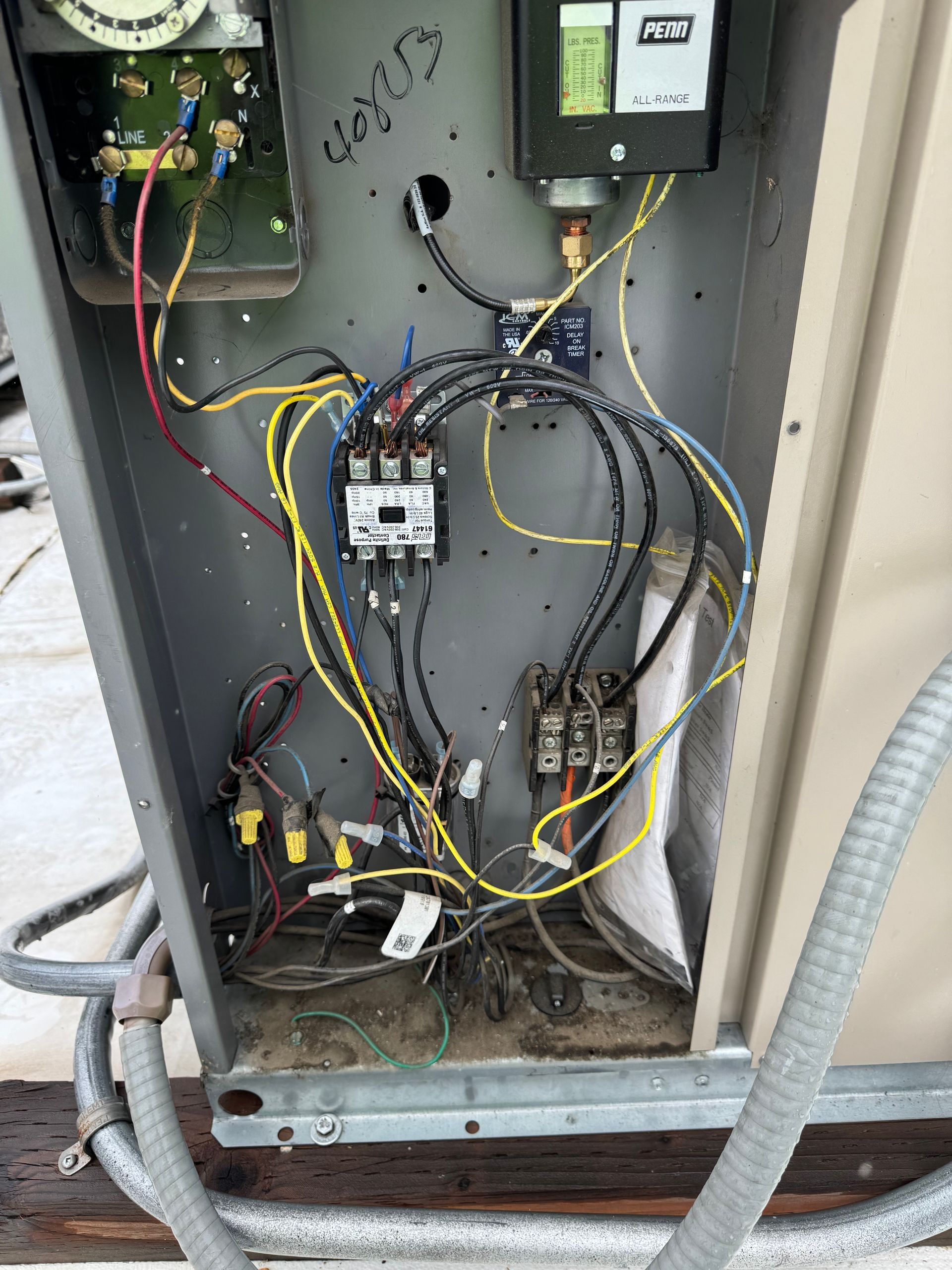 Open electrical control panel with wires, relays, and components inside a metal cabinet.