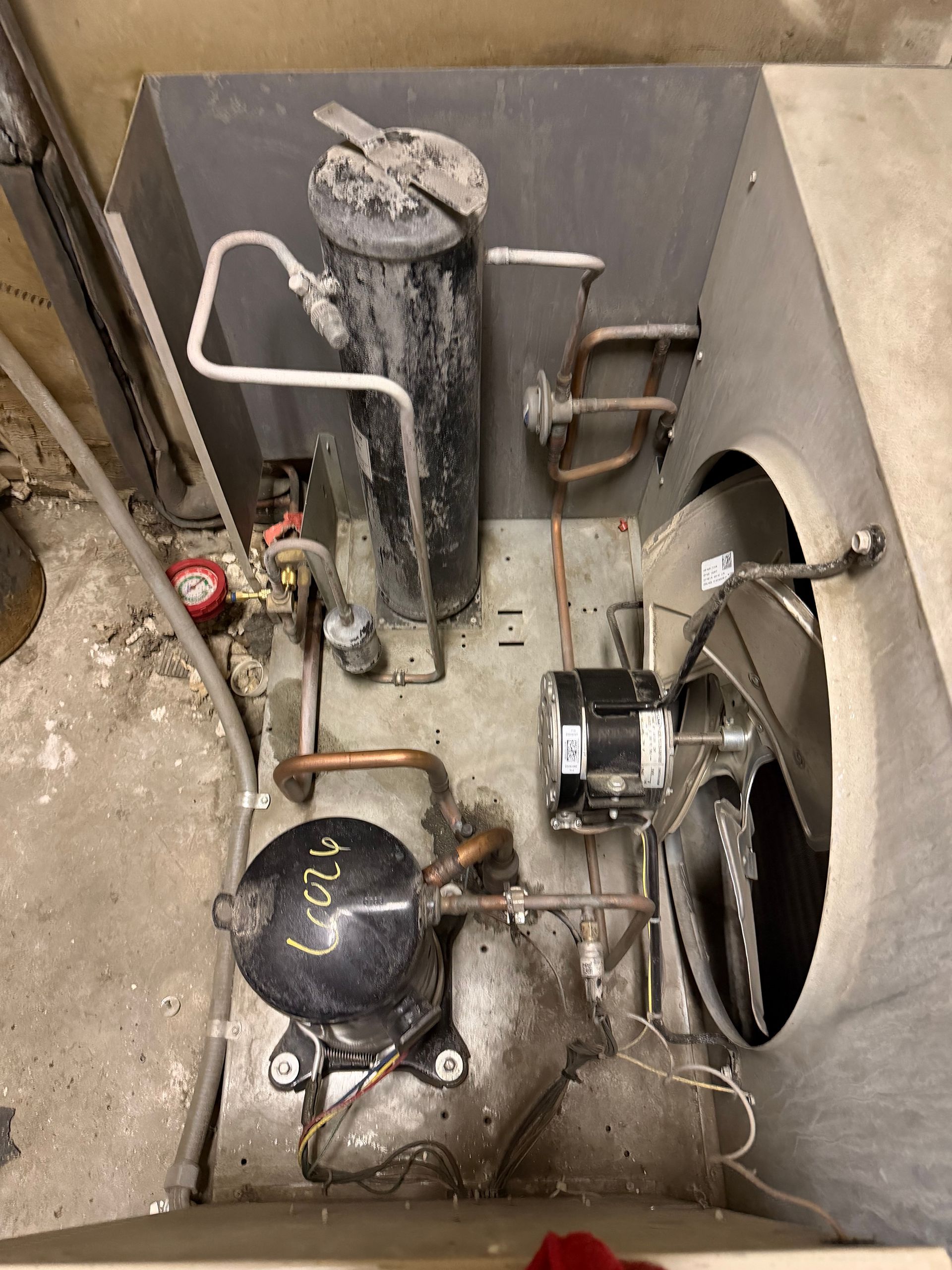 Basement HVAC system with pipes, pressure tank, and duct opening on a concrete floor