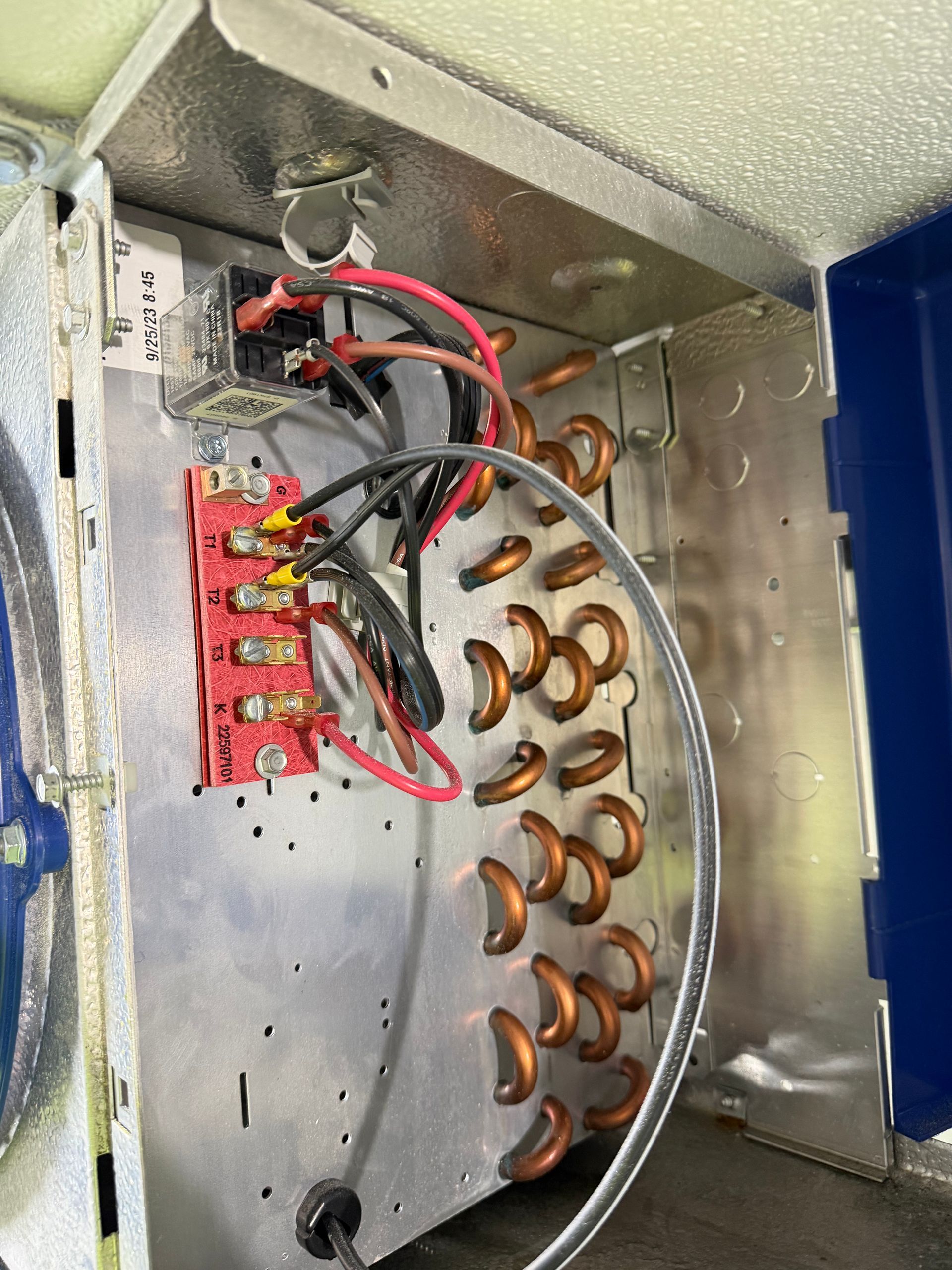 Open electrical panel with wires, terminal block, and copper coils inside a metal box