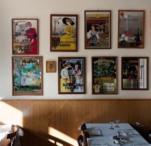 In un accogliente interno di ristorante, una parete con poster vintage incorniciati è posizionata sopra una panca di legno.