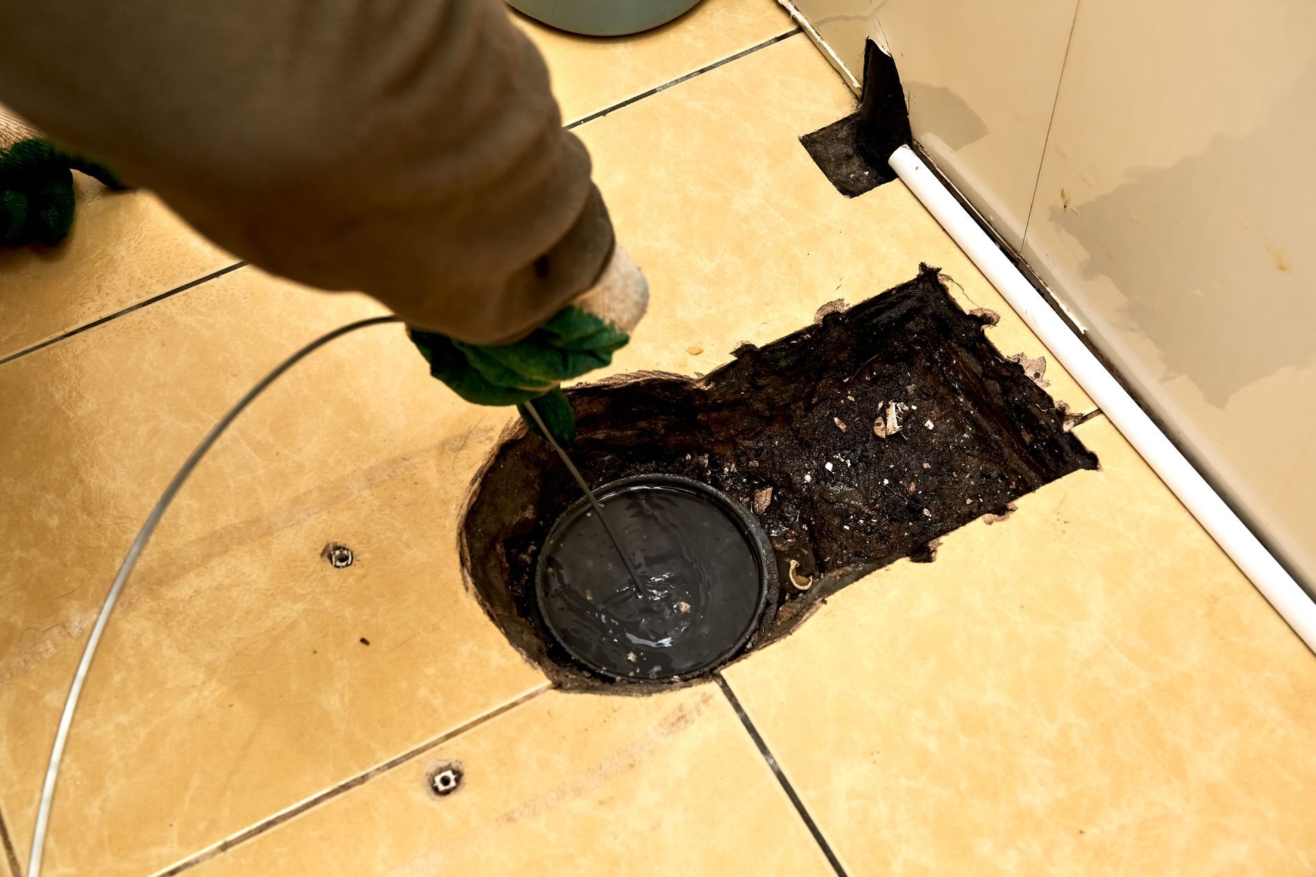 A person is cleaning a hole in the floor with a hose.