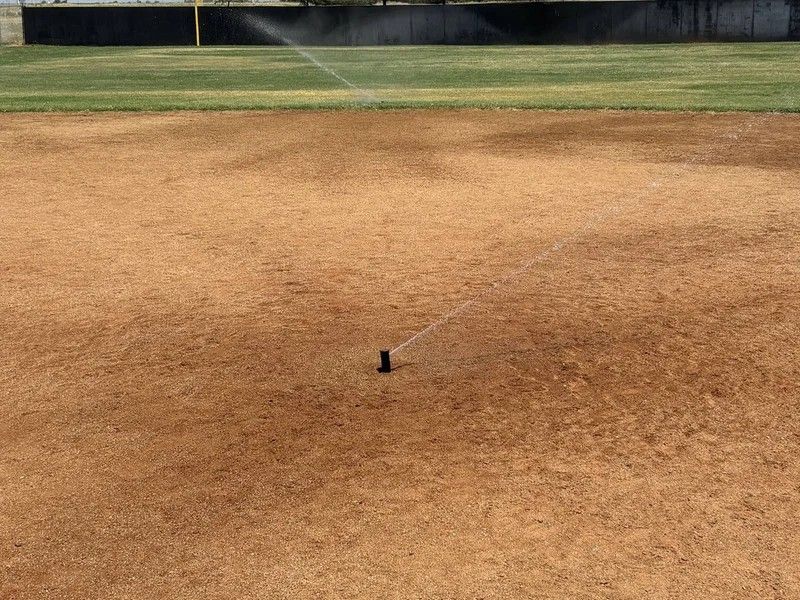 Empty baseball infield with a small black marker on the dirt near center field