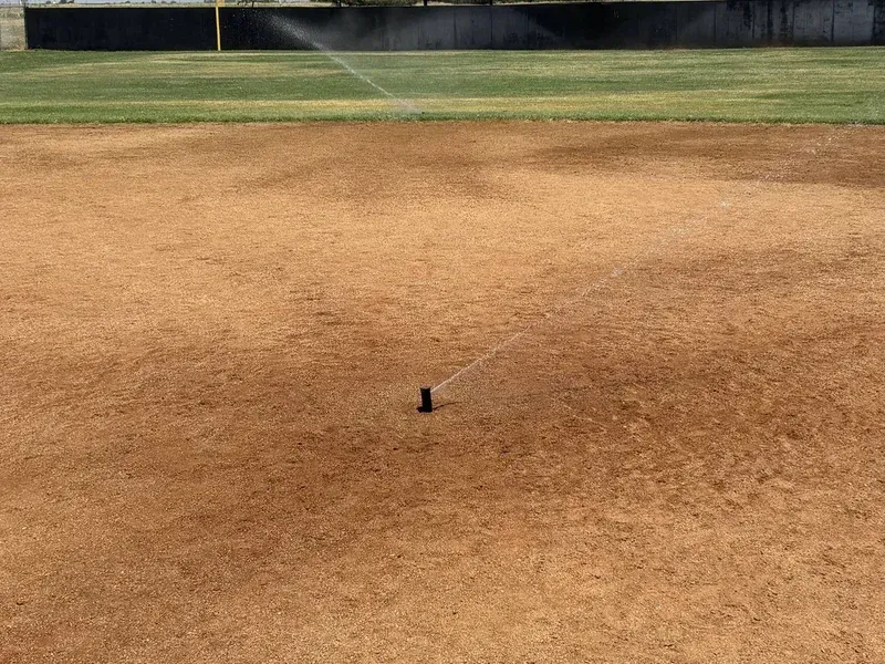 Baseball field infield dirt with a small black marker near the center