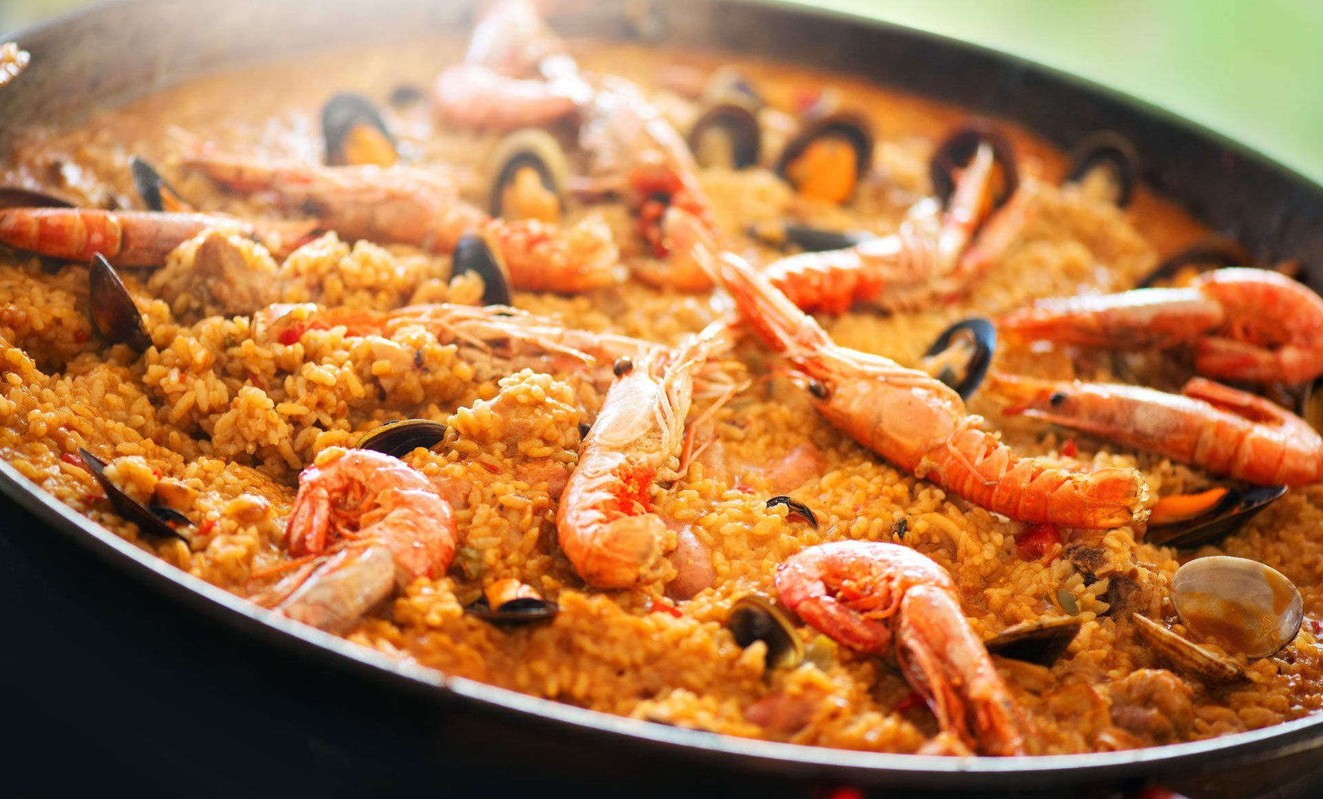 Una padella piena di riso, gamberi, cozze e altri frutti di mare.