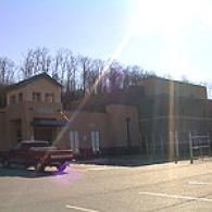 A red truck parked in front of a tan commercial building under a bright, sunny sky with lens flare.