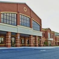A large, modern multi-story brick building with rows of large rectangular windows and a covered entrance walkway.