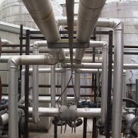 A network of industrial silver-toned metal pipes and supporting structures in an outdoor facility.