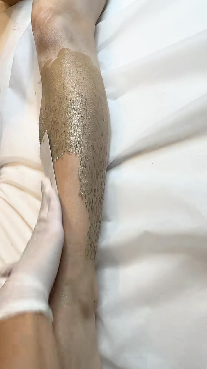 Leg With Depilatory Wax, Being Smoothed by a Gloved Hand on a White Surface — Sage Spa & Beauty in Mackay, QLD