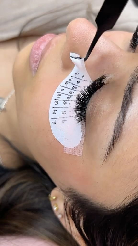Person Receiving Eyelash Extensions; Technician Using Tweezers, Eye Pad With Markings — Sage Spa & Beauty in Mackay, QLD
