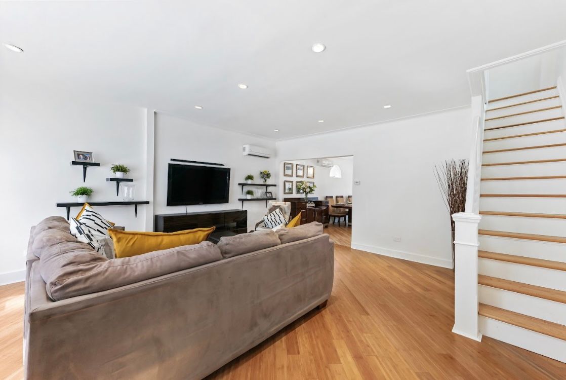 A living room with a couch , television , and stairs.