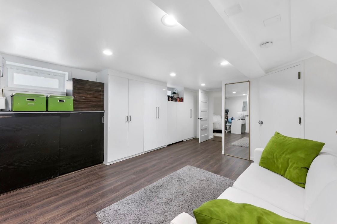 A living room with a white couch and green pillows.