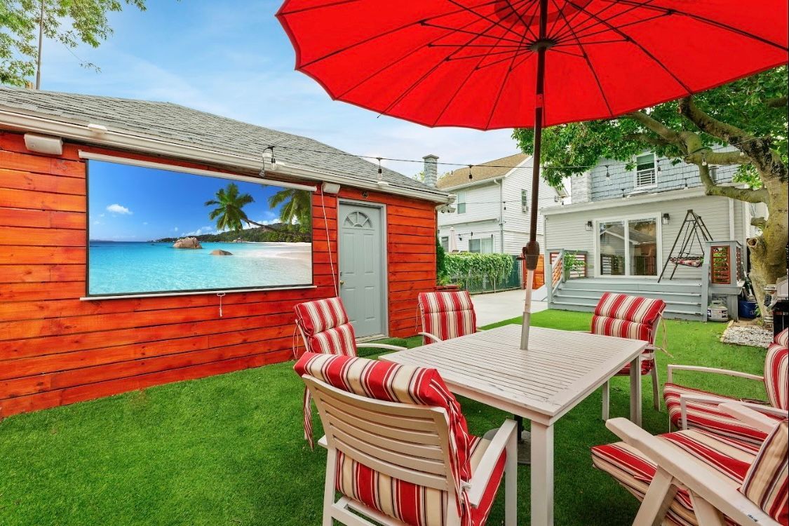 A patio with a table and chairs and a red umbrella.