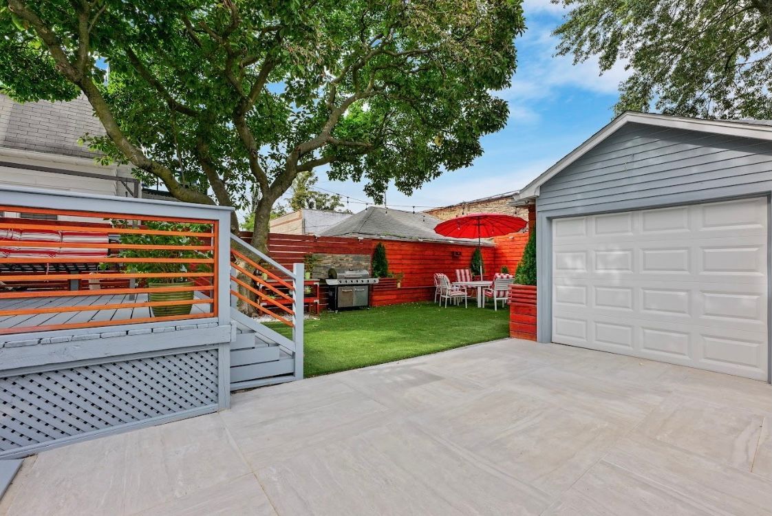 There is a garage with a table and chairs in the backyard.