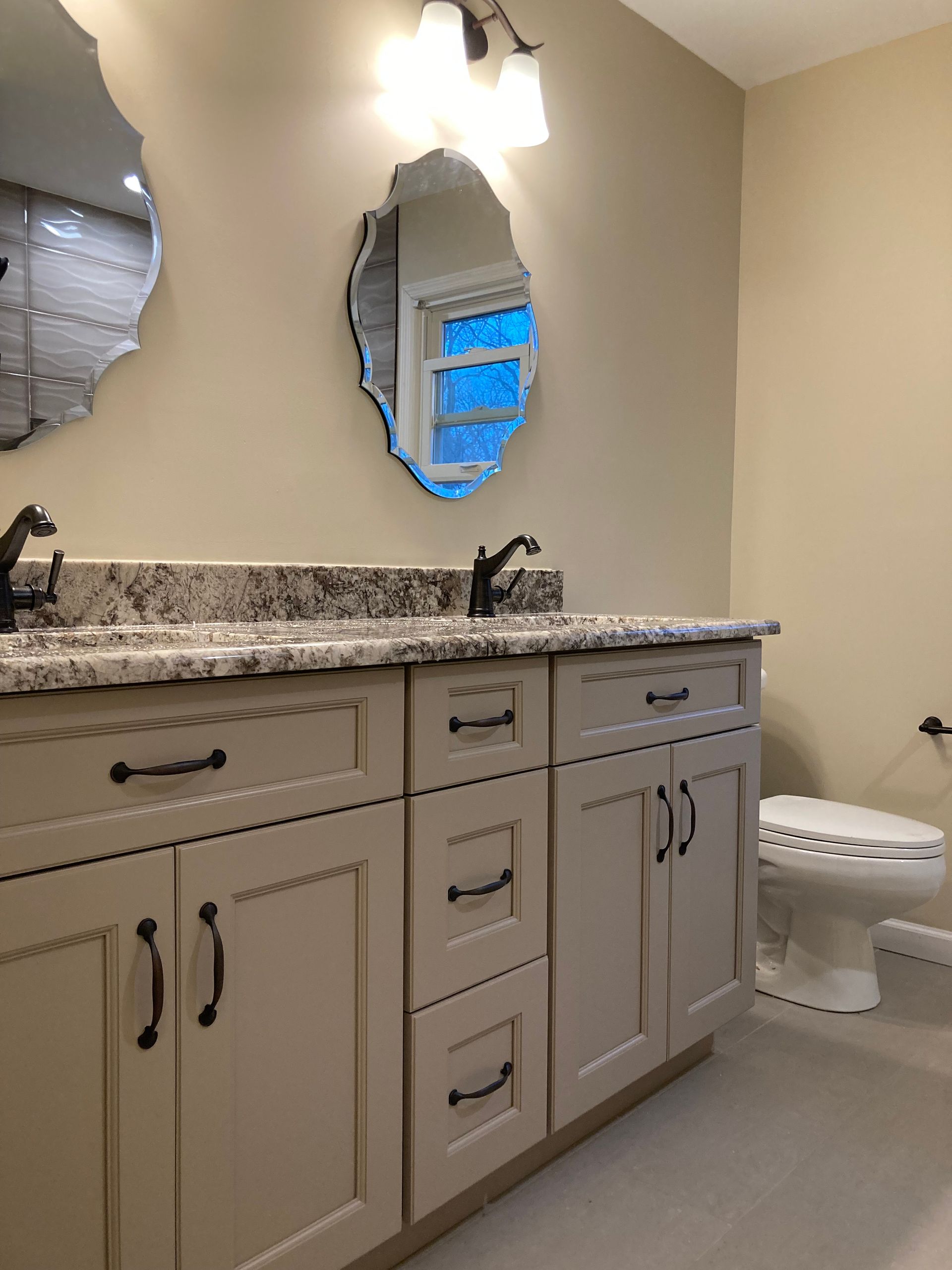 A bathroom with two sinks , a toilet and a mirror.