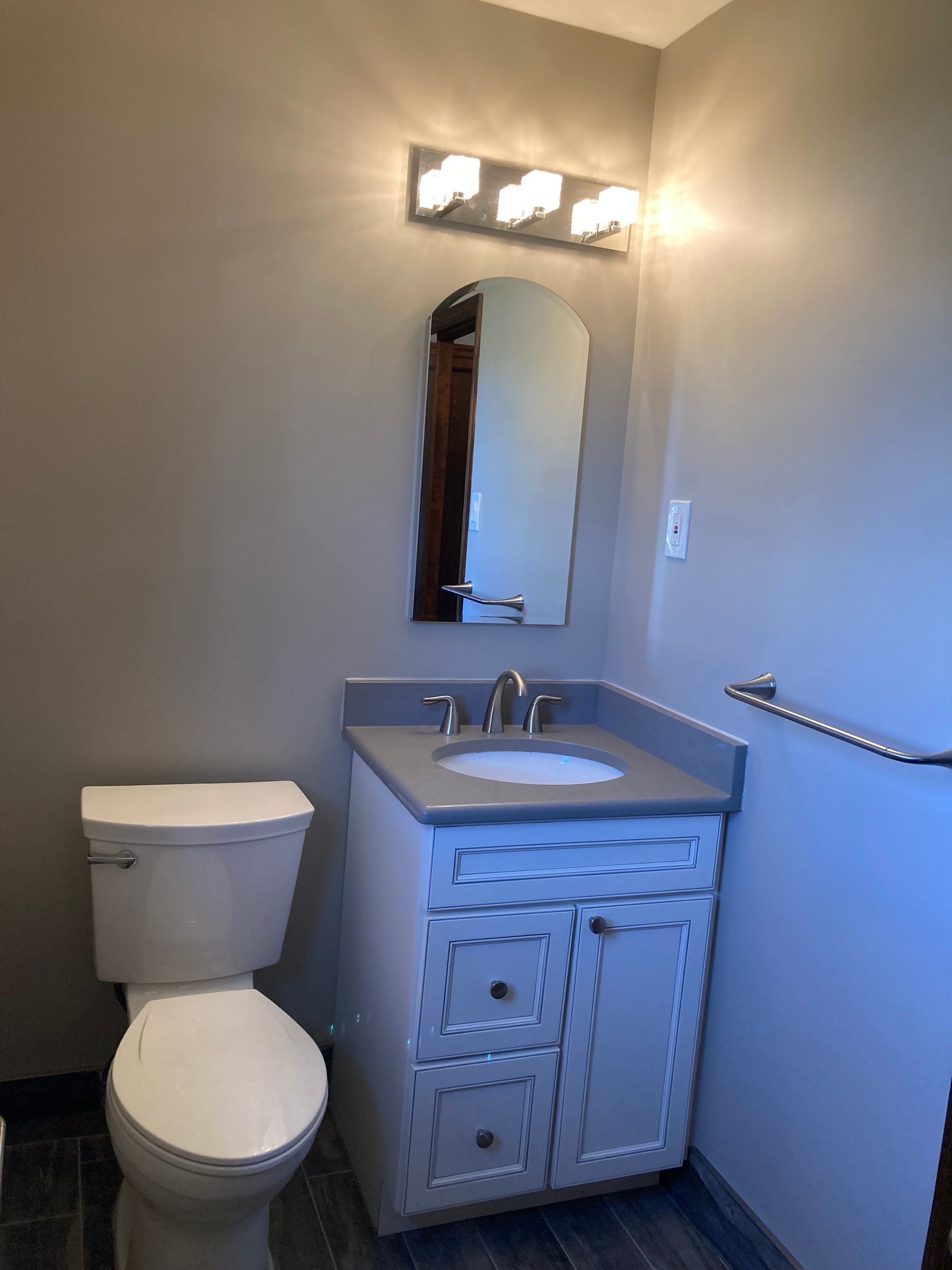 A bathroom with a toilet , sink and mirror.
