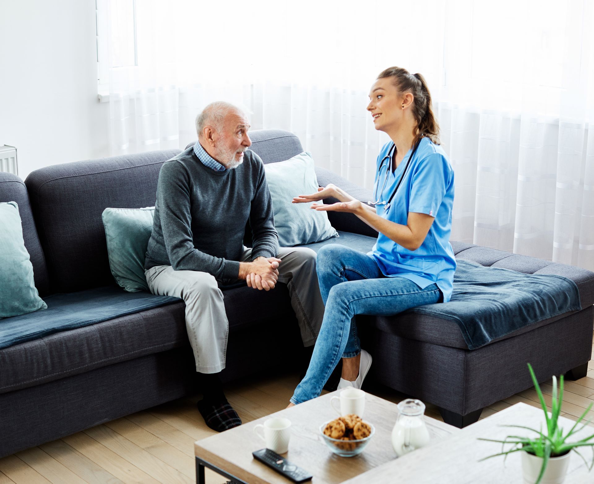in-home caregiver speaking to male patient on couch