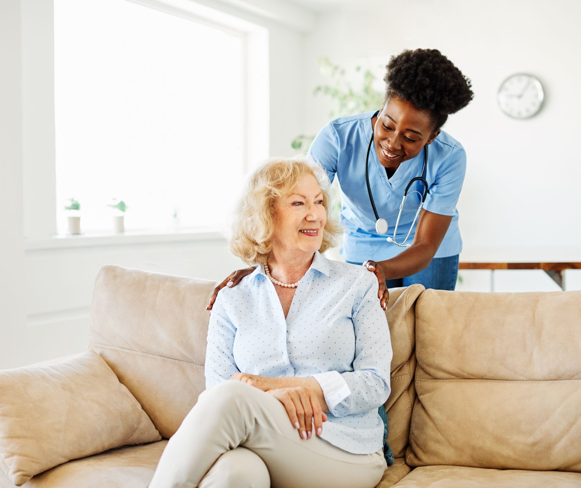 caretaker placing hands on shoulders of elderly female patient