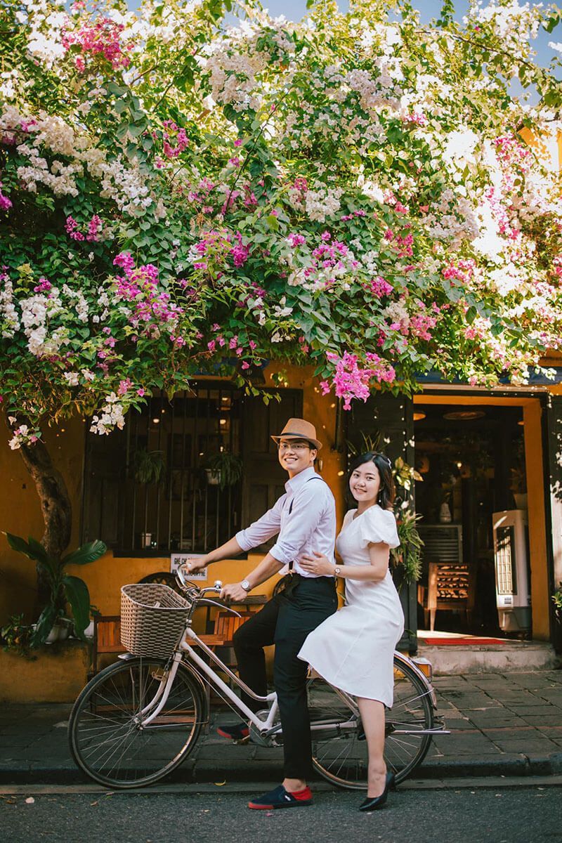 A happy couple riding a bicycle in Hoi An, enjoying a peaceful and romantic escape in Vietnam.