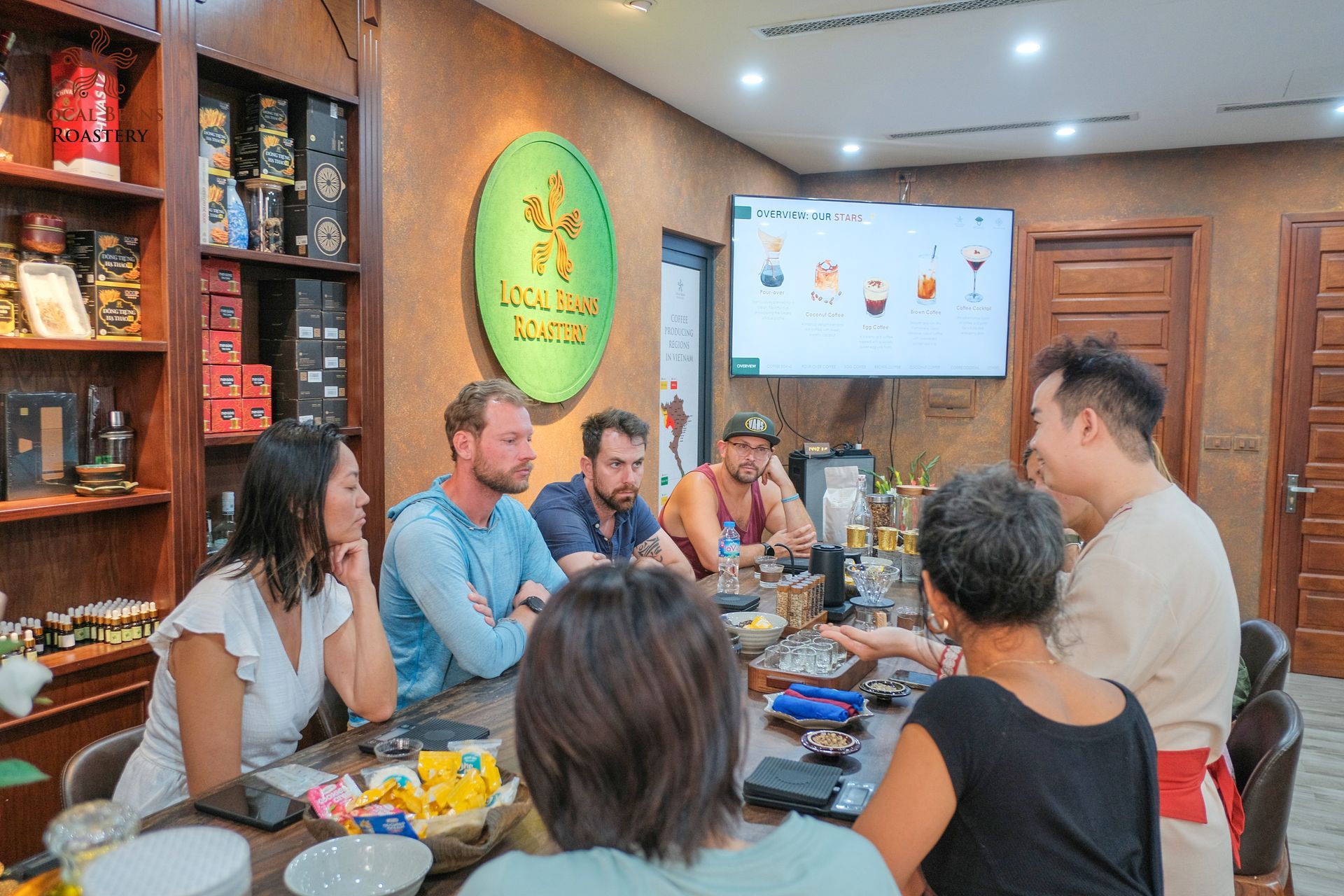 A group of people gathered around a table in Local Beans Roastery, enjoying a coffee experience and learning about Vietnamese coffee culture.