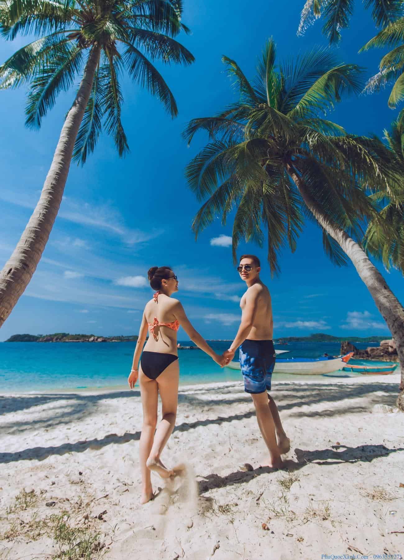 A couple holding hands on Phu Quoc’s white sand beach, the perfect tropical escape for lovebirds.
