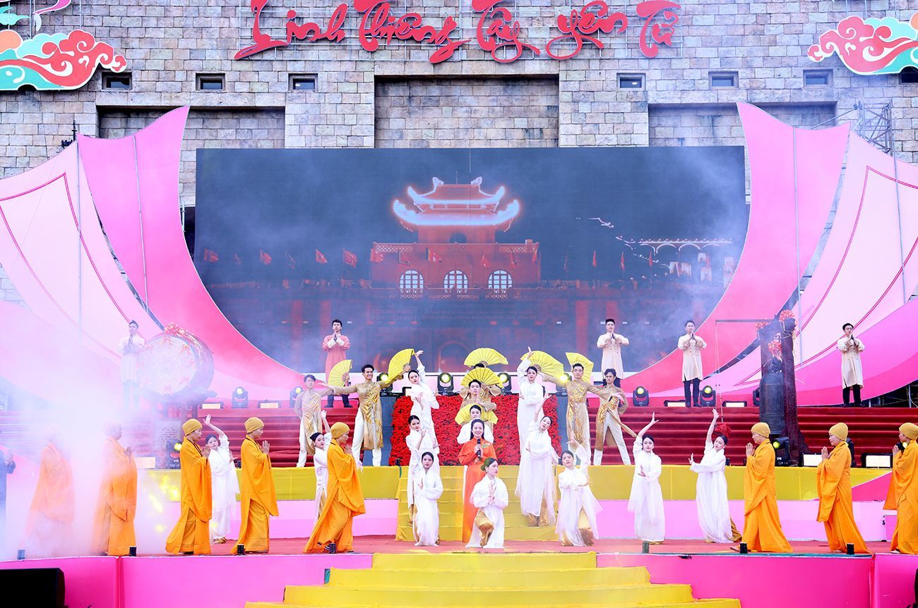 A grand stage performance during a Vietnamese spring festival, featuring dancers in yellow and white costumes with a misty backdrop.