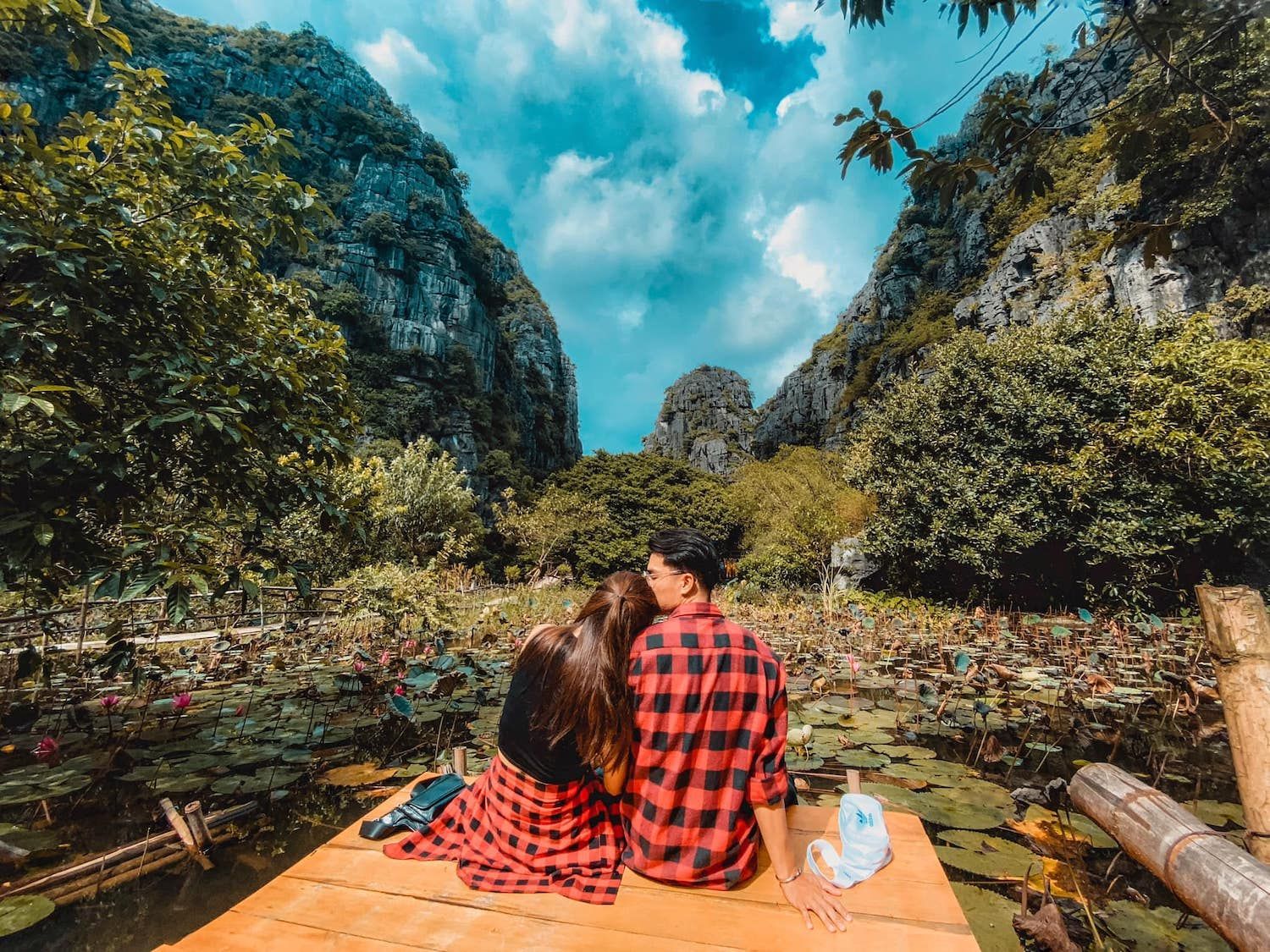 A couple on a serene boat ride in Ninh Binh, surrounded by stunning limestone karsts and lotus fields.