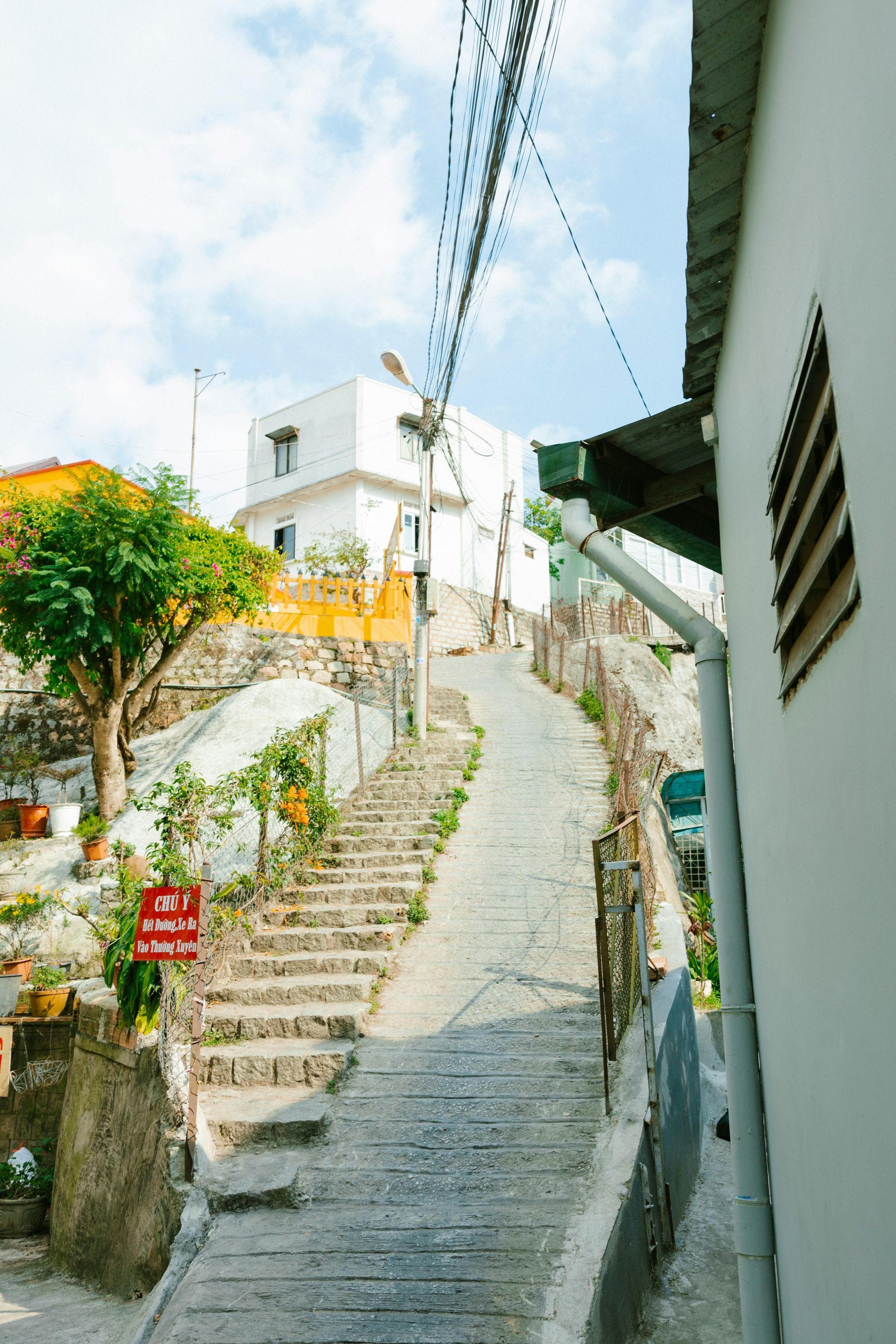 A scenic stone stairway in Vietnam, leading to charming white houses and lush greenery, perfect for couples.