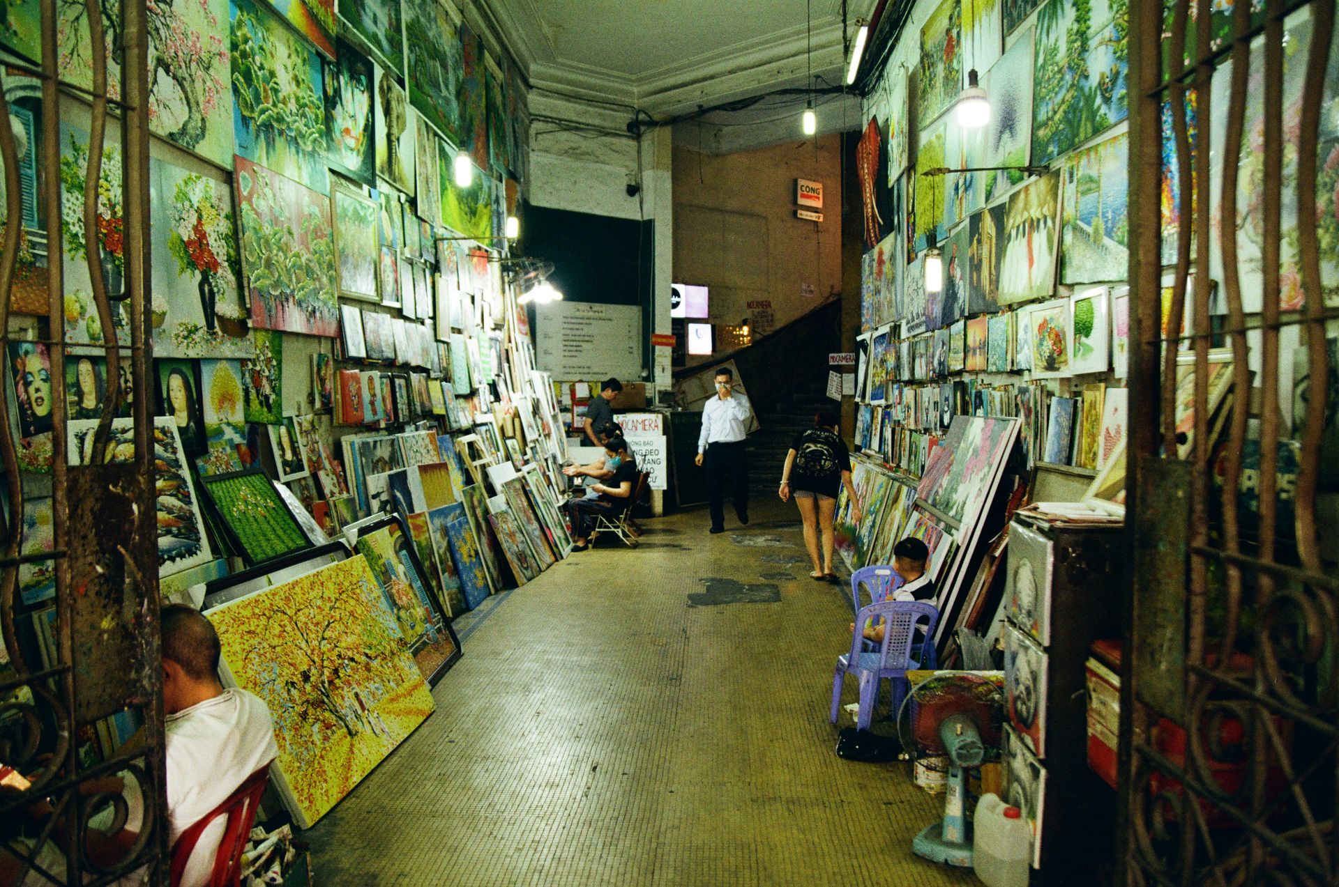 A bustling Vietnamese art shop displaying paintings in a vibrant alley.