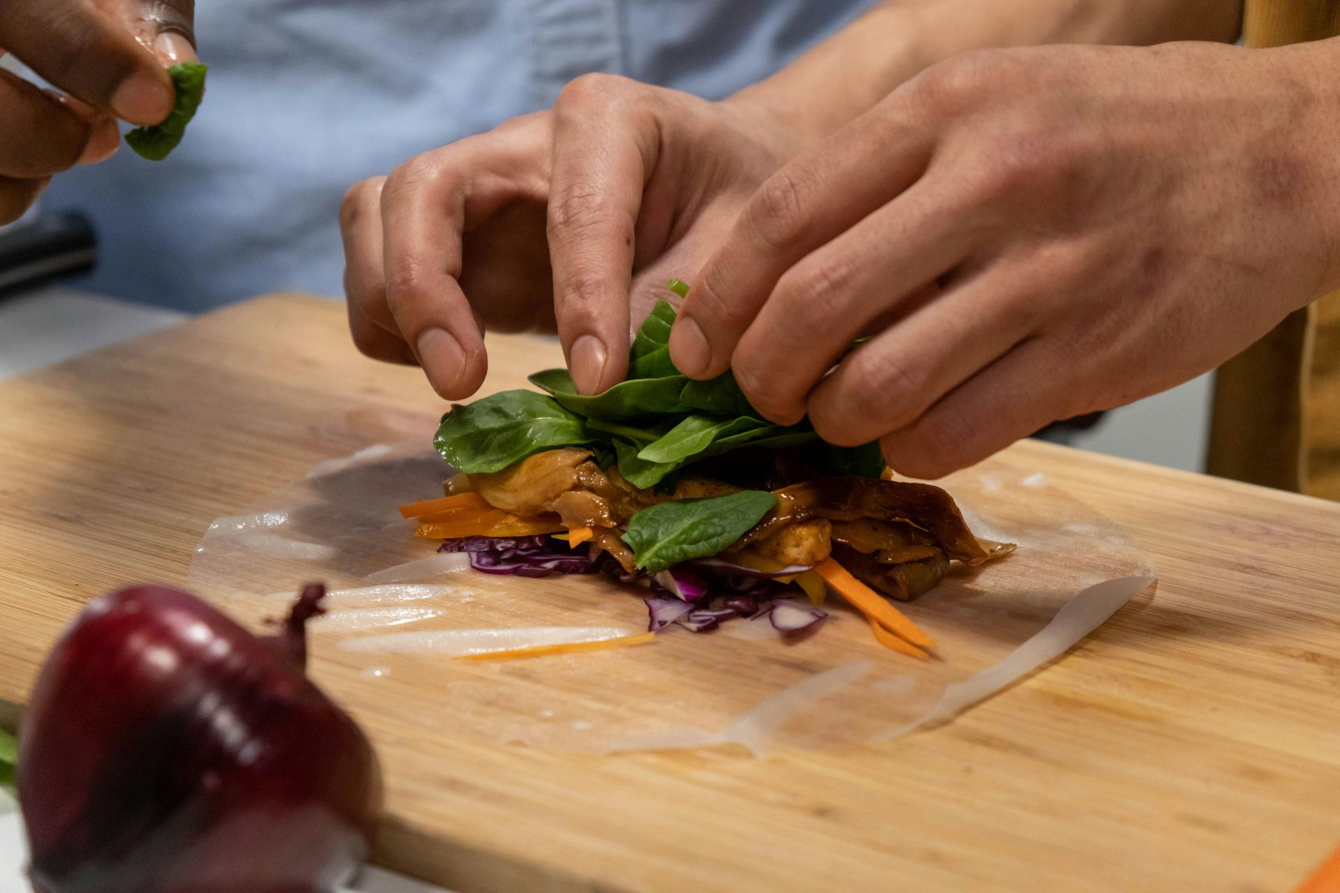 Fresh spring rolls being rolled by hand, highlighting Vietnamese culinary traditions.