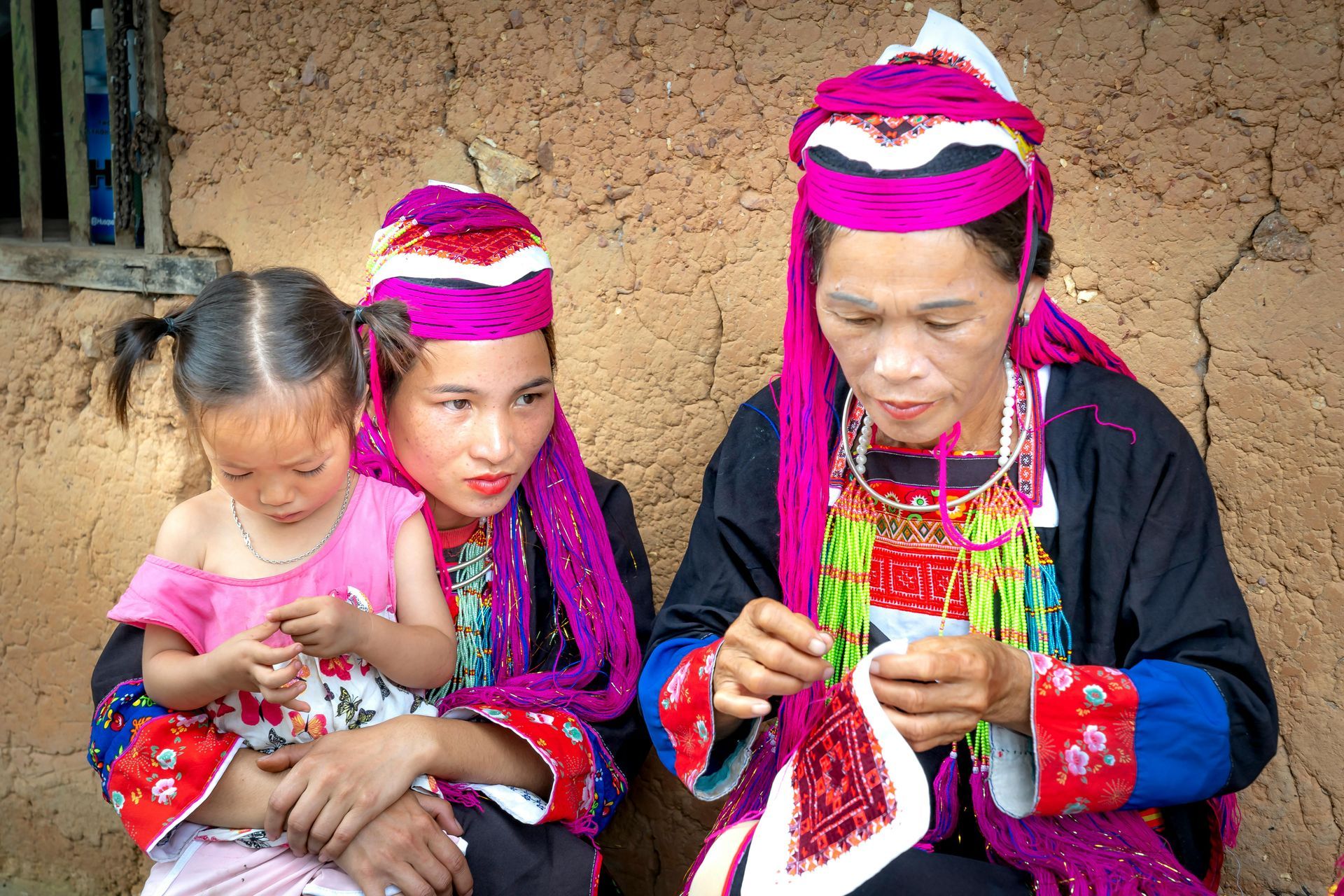 A woman and a little girl diligently crafting silk products in a traditional village setting.
