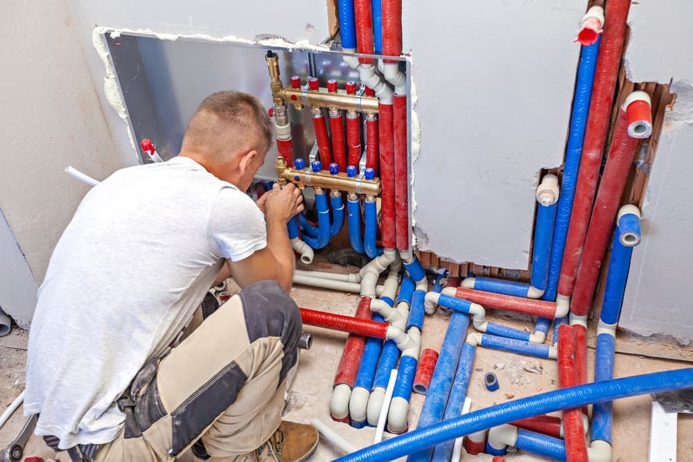 A Plumber Is Working on A Heating System in A Bathroom — Custys Plumbing Services in Ellis Beach, QLD