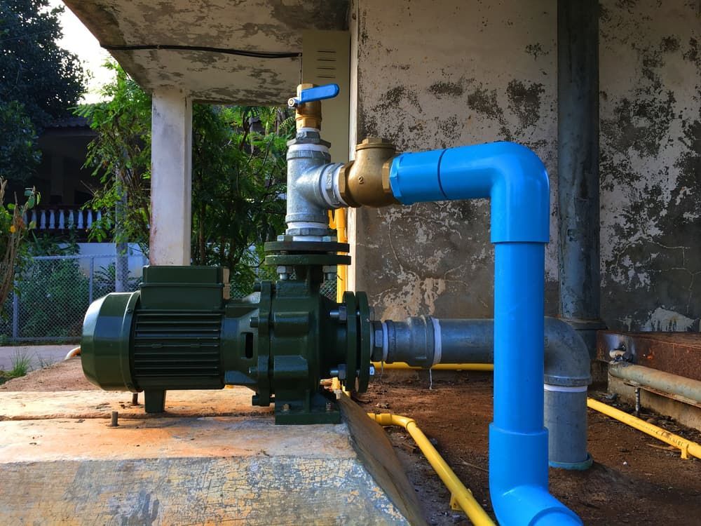 A Green Pump Is Connected to A Blue Pipe — Custys Plumbing Services in Trinity Park, QLD