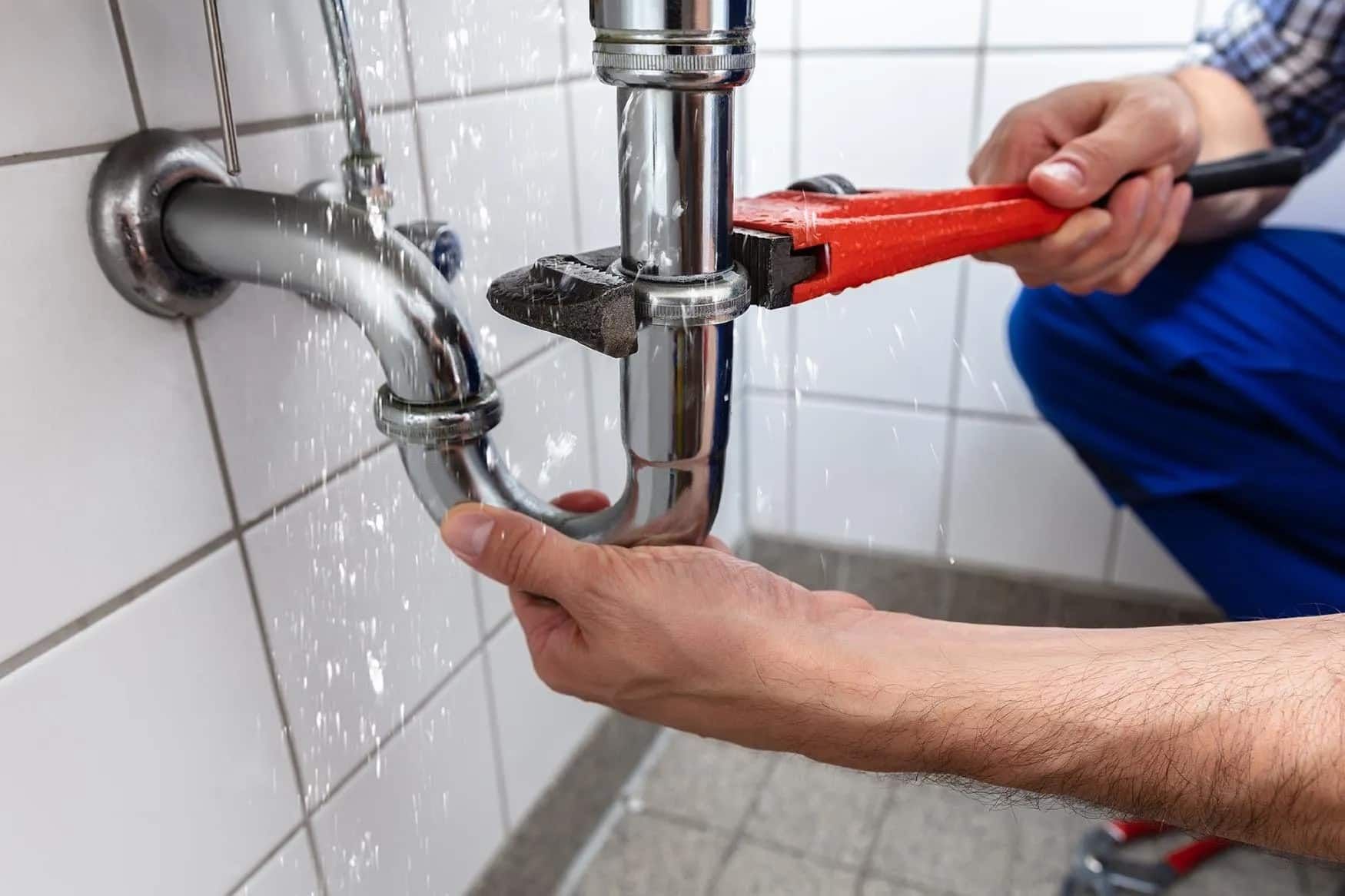 A Plumber Is Fixing a Pipe in A Bathroom with A Wrench — Custys Plumbing Services in Trinity Park, QLD