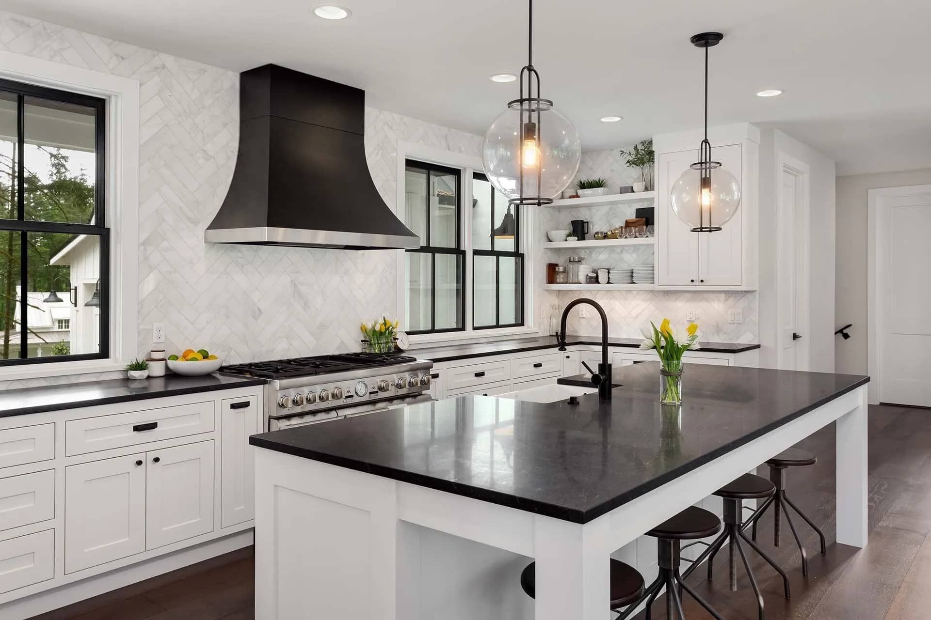A Kitchen with White Cabinets , Black Counter Tops , and A Large Island — Custys Plumbing Services in Trinity Park, QLD