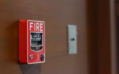 Red fire alarm on a wall beside a metal switch plate Red fire alarm on a wall beside a metal switch plate